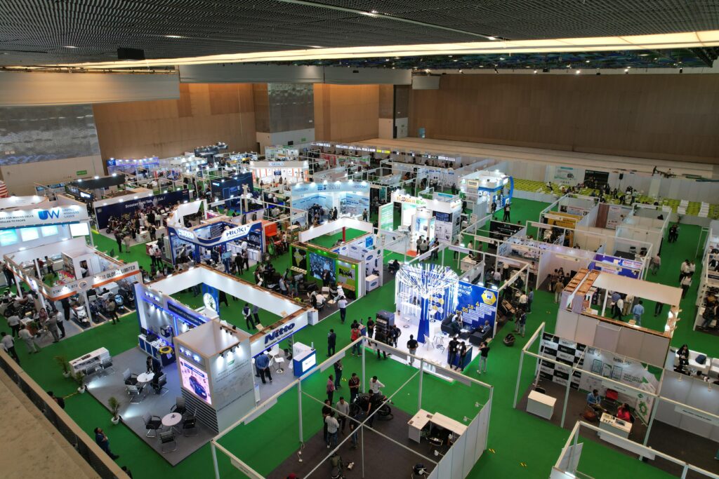 Professional delegates in business attire discussing industrial hardware and technical equipment at an exhibition booth.